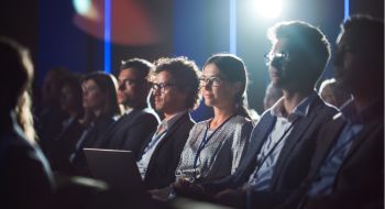 a businesswoman sits in the crowd at a corporate conference