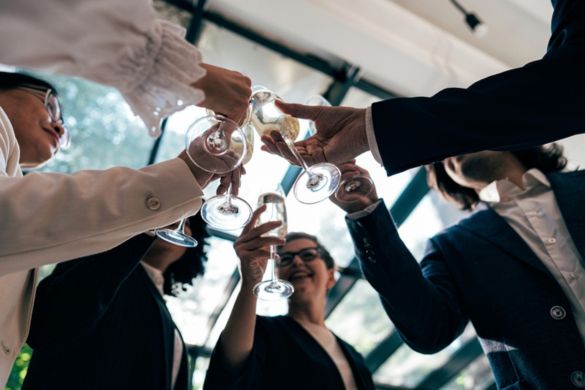 a corporate team clink wine glasses at an event